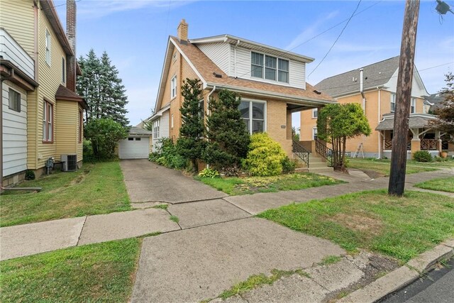 view of front of house featuring a garage, an outbuilding, central AC unit, and a front yard