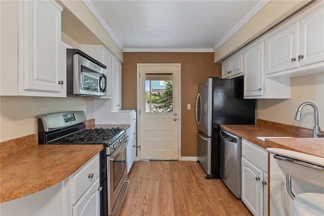 kitchen featuring ornamental molding, light hardwood / wood-style flooring, white cabinetry, and stainless steel appliances