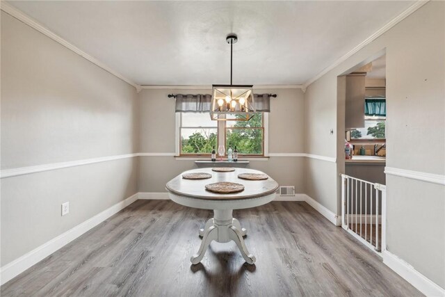 unfurnished dining area featuring hardwood / wood-style flooring, crown molding, sink, and a chandelier