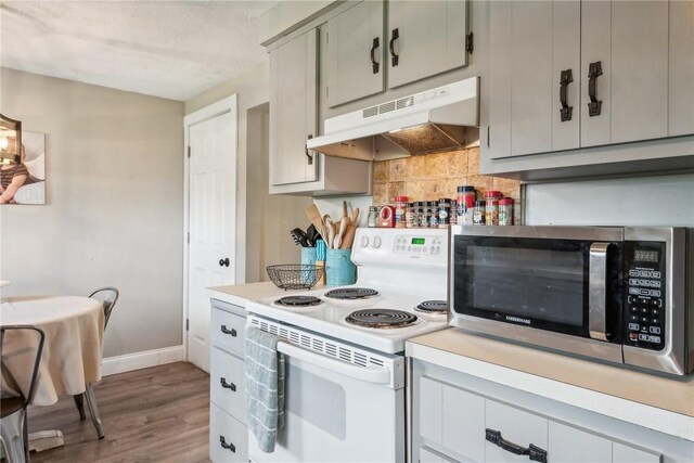 kitchen featuring gray cabinets, white electric stove, hardwood / wood-style flooring, and tasteful backsplash