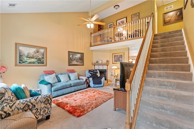 living room featuring carpet flooring, a tile fireplace, high vaulted ceiling, and ceiling fan