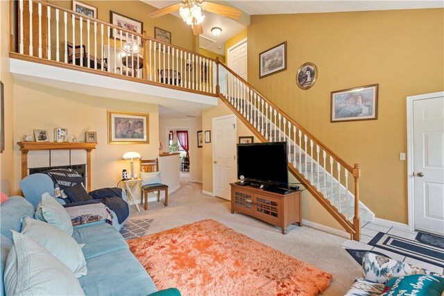 carpeted living room featuring a tile fireplace, high vaulted ceiling, and ceiling fan