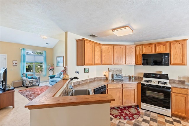 kitchen with a peninsula, a sink, visible vents, light countertops, and black appliances