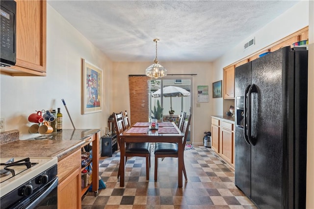 kitchen featuring a textured ceiling, dark floors, visible vents, hanging light fixtures, and black appliances