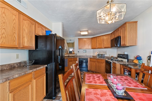 kitchen featuring a chandelier, a textured ceiling, hanging light fixtures, and black appliances