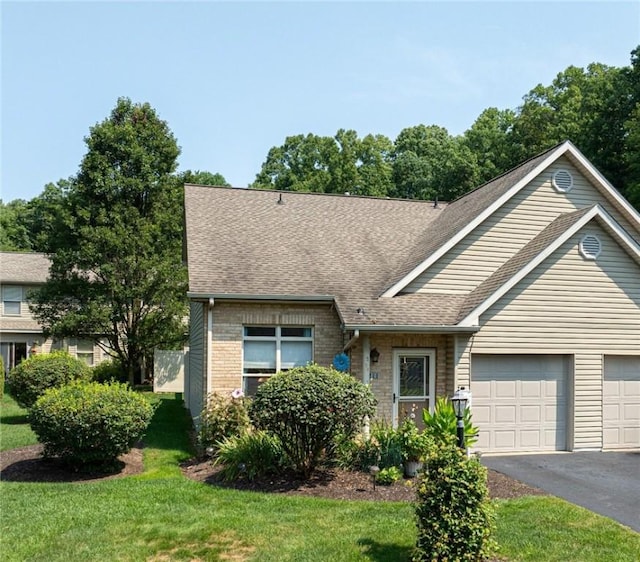 view of front of house with brick siding, a shingled roof, an attached garage, a front yard, and driveway