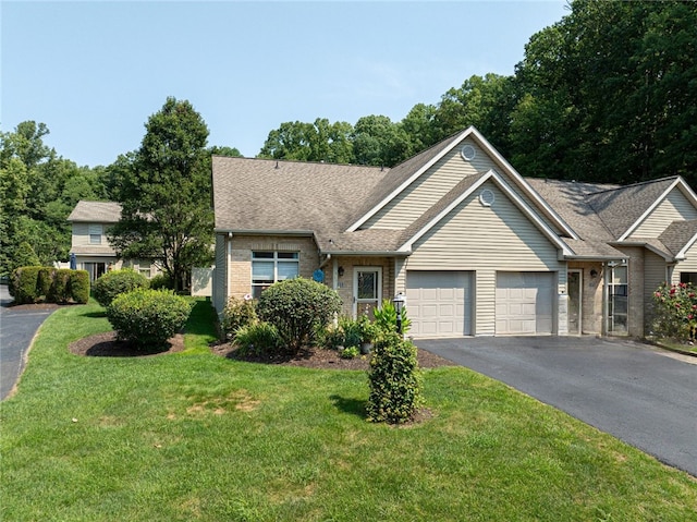 view of front of house with driveway, a shingled roof, an attached garage, and a front yard