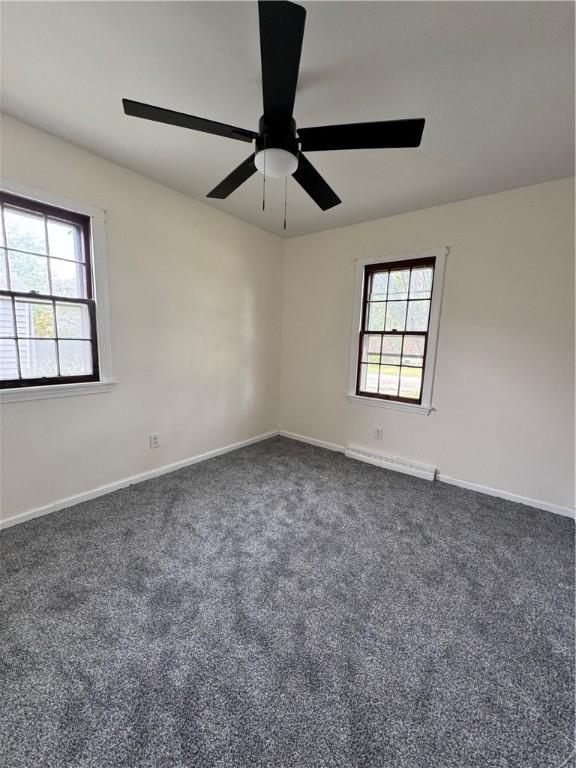 carpeted spare room with a baseboard radiator and ceiling fan