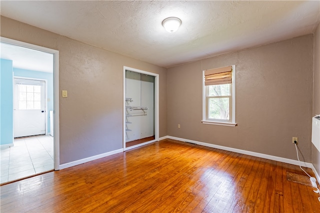 unfurnished bedroom featuring a closet, wood-type flooring, and a textured ceiling