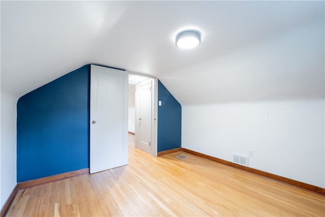 additional living space featuring vaulted ceiling and hardwood / wood-style flooring