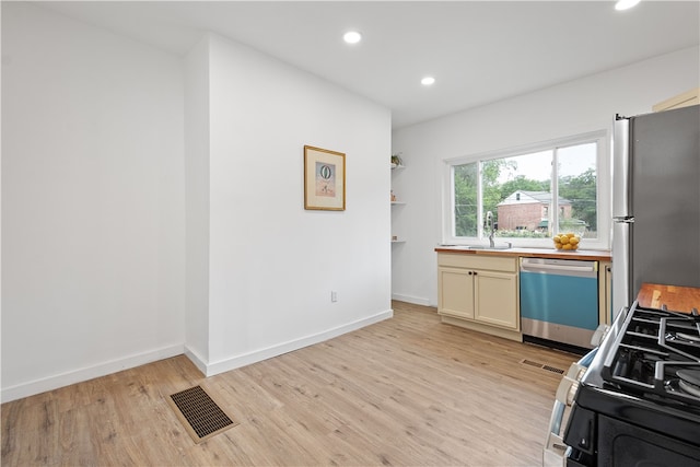 kitchen with appliances with stainless steel finishes, light hardwood / wood-style floors, and sink