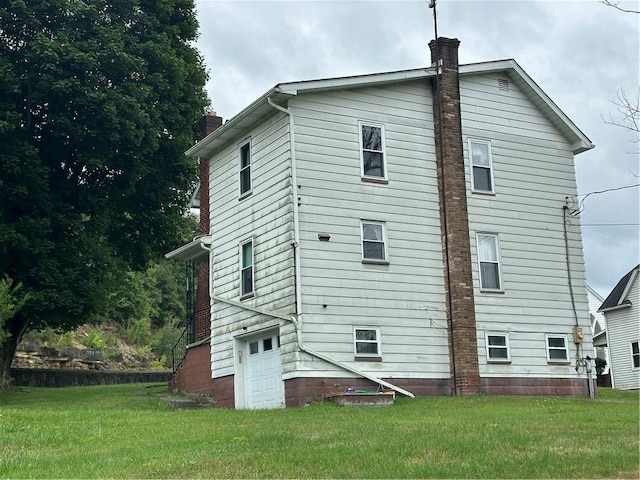 back of house with a garage and a lawn