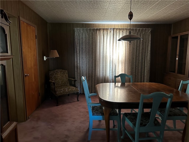 dining room featuring carpet and wood walls