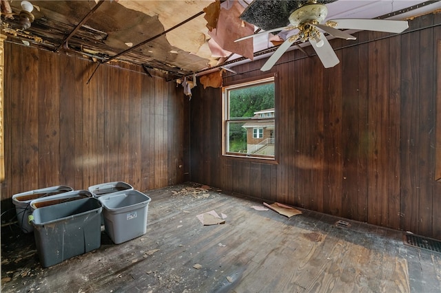 unfurnished room featuring wood walls, ceiling fan, and hardwood / wood-style floors