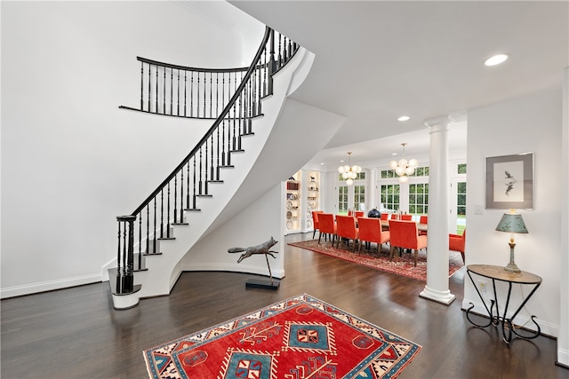 entrance foyer featuring ornate columns, an inviting chandelier, and hardwood / wood-style floors