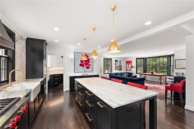 kitchen with hanging light fixtures, sink, dark hardwood / wood-style floors, a kitchen island, and backsplash