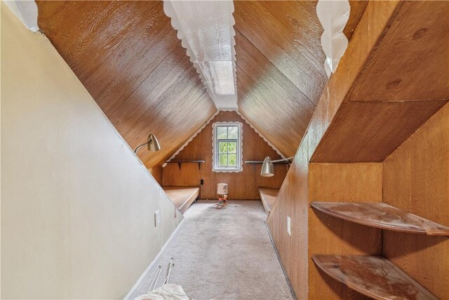 interior space featuring vaulted ceiling, light carpet, wooden walls, and wooden ceiling