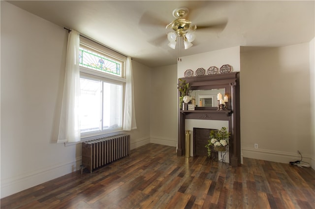 unfurnished living room featuring dark hardwood / wood-style flooring, radiator heating unit, and a wealth of natural light