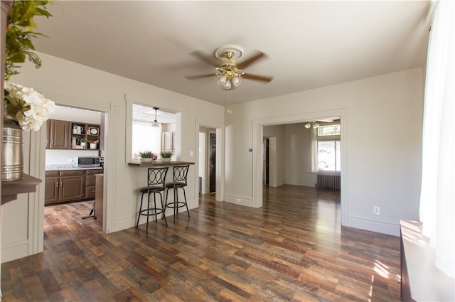 unfurnished living room featuring ceiling fan, radiator heating unit, and dark hardwood / wood-style floors