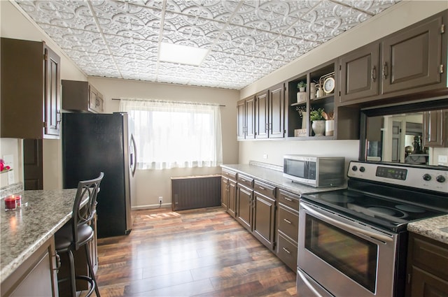 kitchen with appliances with stainless steel finishes, light stone counters, and wood-type flooring