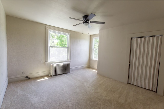 carpeted spare room with ceiling fan and radiator