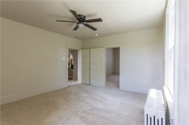 unfurnished bedroom with light carpet, radiator heating unit, and ceiling fan