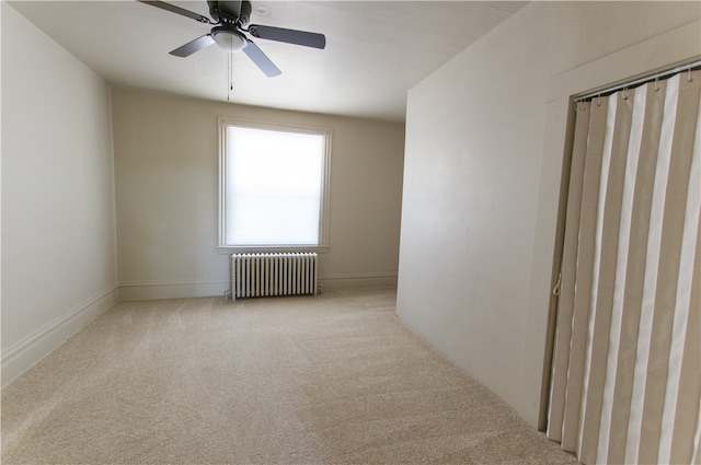 carpeted spare room with ceiling fan and radiator heating unit