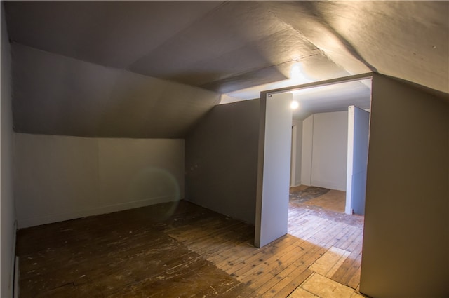 additional living space with hardwood / wood-style floors and lofted ceiling