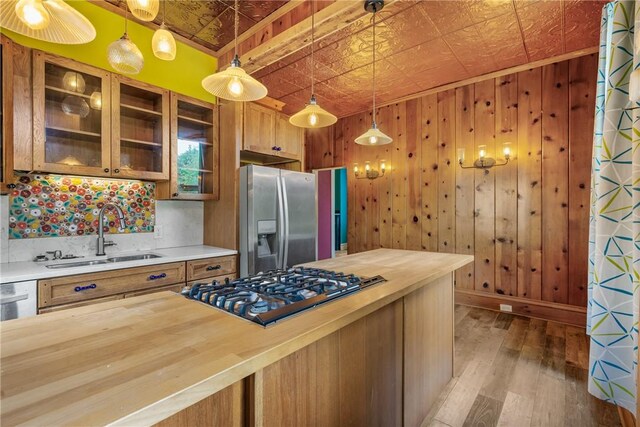 kitchen featuring stainless steel appliances, hanging light fixtures, backsplash, hardwood / wood-style flooring, and sink