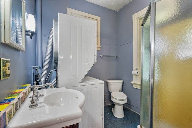 bathroom featuring stacked washer / dryer, vanity, tile patterned flooring, and toilet