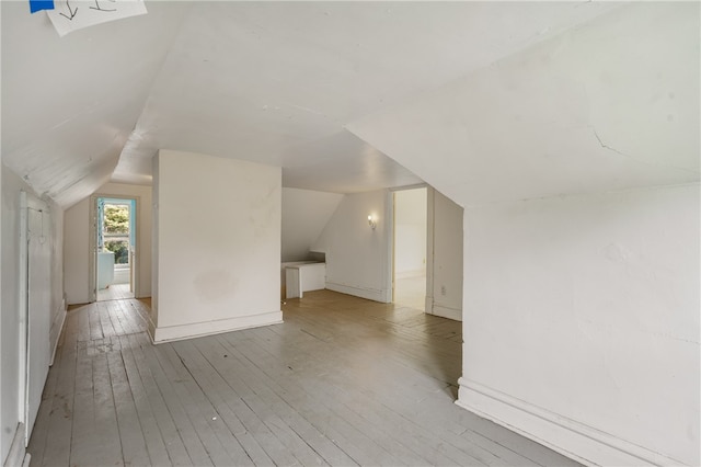 additional living space with light wood-type flooring and vaulted ceiling