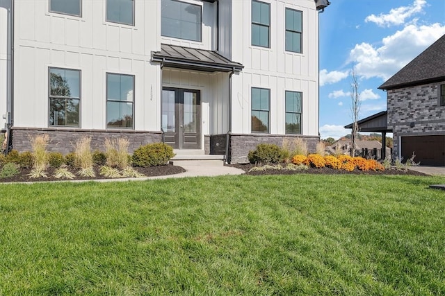 entrance to property featuring french doors, a lawn, and a garage