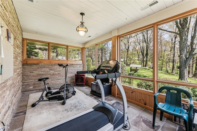 workout area featuring brick wall and light tile patterned floors