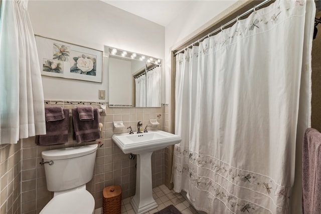 bathroom with tile patterned floors, tile walls, toilet, and backsplash