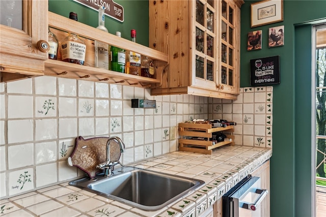 kitchen with tile counters, tasteful backsplash, sink, and dishwashing machine