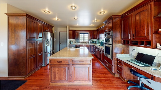 kitchen featuring decorative backsplash, appliances with stainless steel finishes, dark wood-type flooring, and a center island