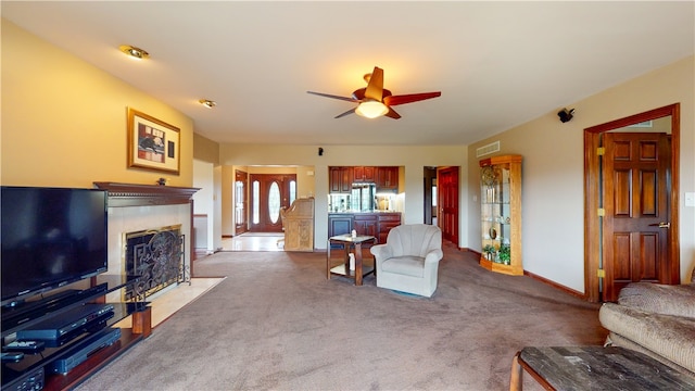 carpeted living room with ceiling fan and a tile fireplace