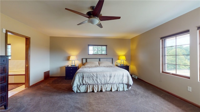 carpeted bedroom featuring ceiling fan, ensuite bathroom, and multiple windows