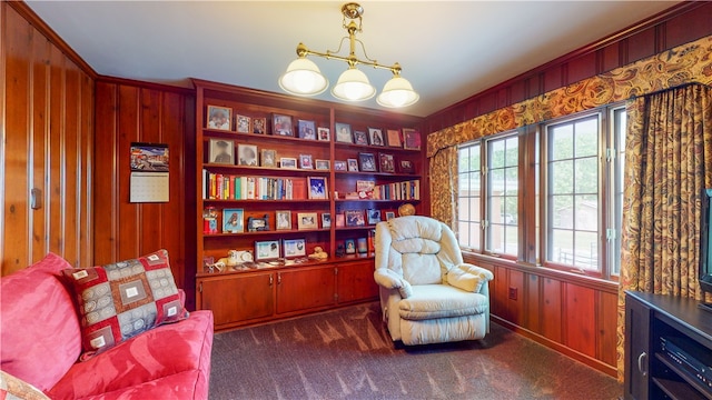 sitting room with wooden walls, dark colored carpet, and built in features