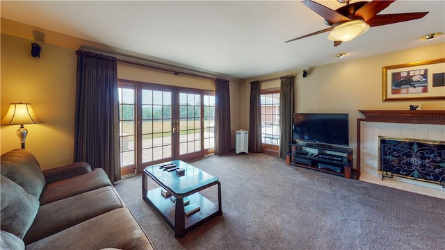 living room featuring ceiling fan, radiator heating unit, french doors, a fireplace, and light colored carpet