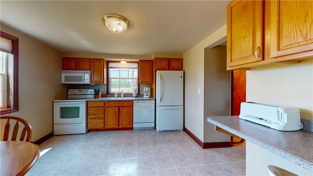 kitchen featuring white appliances, sink, and light tile patterned floors