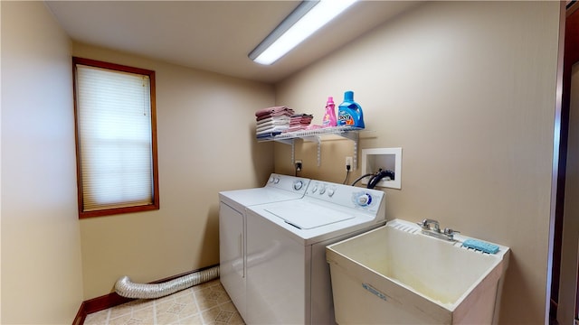 clothes washing area with washing machine and clothes dryer, light tile patterned floors, and sink