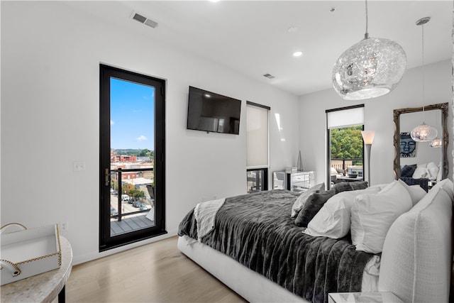 bedroom with multiple windows, light hardwood / wood-style flooring, and access to outside