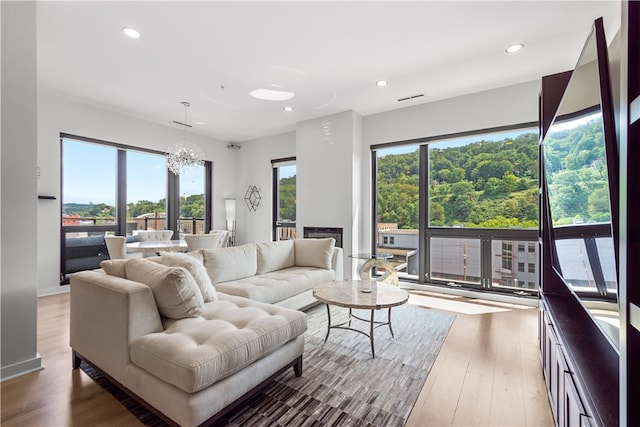 living room featuring hardwood / wood-style floors, a fireplace, a chandelier, and a healthy amount of sunlight