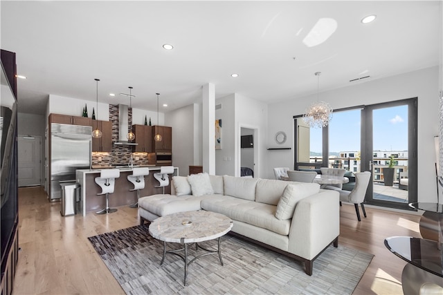 living room with light hardwood / wood-style flooring, an inviting chandelier, and sink