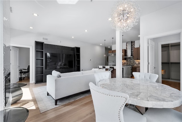 dining area with light hardwood / wood-style flooring, a notable chandelier, and sink