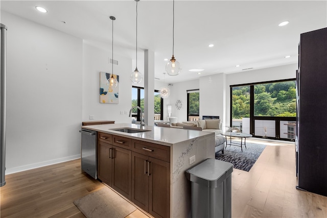 kitchen featuring an island with sink, hardwood / wood-style floors, sink, and hanging light fixtures