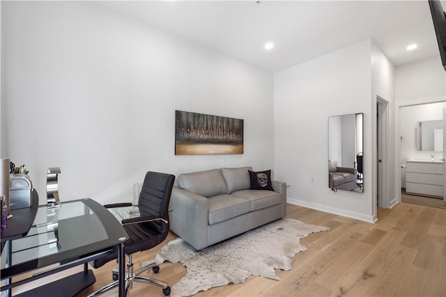 office space featuring light wood-type flooring, baseboards, recessed lighting, and a sink