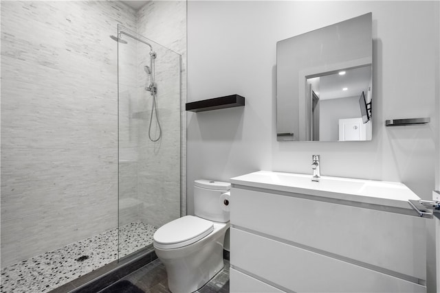 bathroom featuring tiled shower, toilet, and vanity