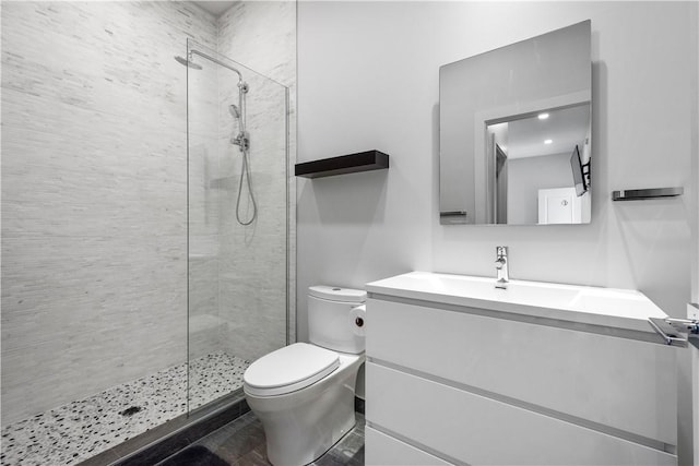 full bath featuring a tile shower, toilet, and vanity